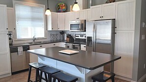 A modern kitchen with a central island, stainless steel appliances, and bar stools. - View - Beautiful home - 2 kitchens #198 (Osoyoos)