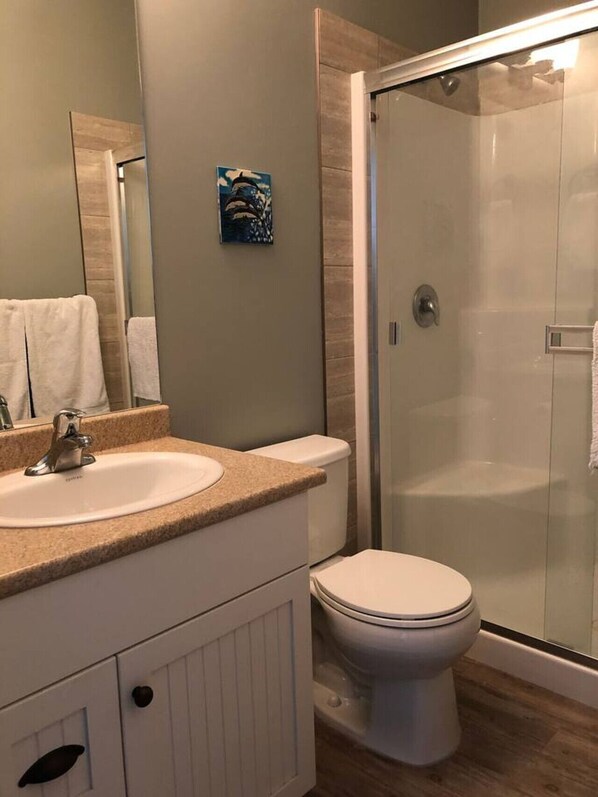 A bathroom with a sink, toilet, and glass shower enclosure.
