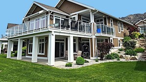 A two-story house with a balcony, a covered patio, and a well-maintained lawn. - View - Beautiful home - 2 kitchens #198 (Osoyoos)