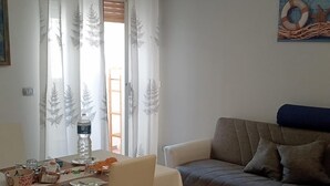 Una zona de menjador amb una taula preparada per a dues persones, un sofà i un quadre a la paret.