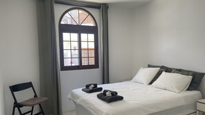 Une chambre à coucher avec un lit, une chaise, une fenêtre et une vue sur l’extérieur.