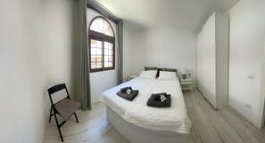 A bedroom with a large bed, a chair, a nightstand, and a window with curtains. - Modern 2 bed apartment (70qm2)  with  oceanview (Costa Adeje)