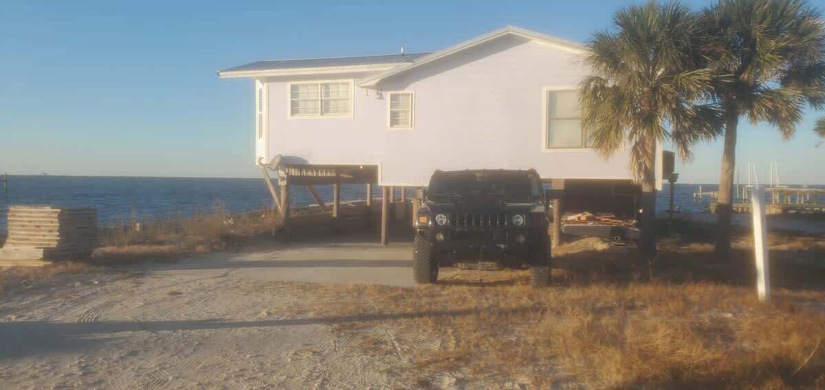 A house with a garage, a dirt driveway, and a parked vehicle.