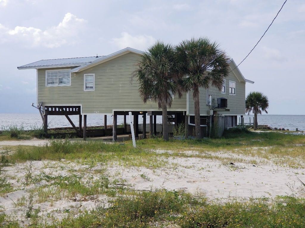Une maison à deux étages avec un balcon, située près d’une plage.