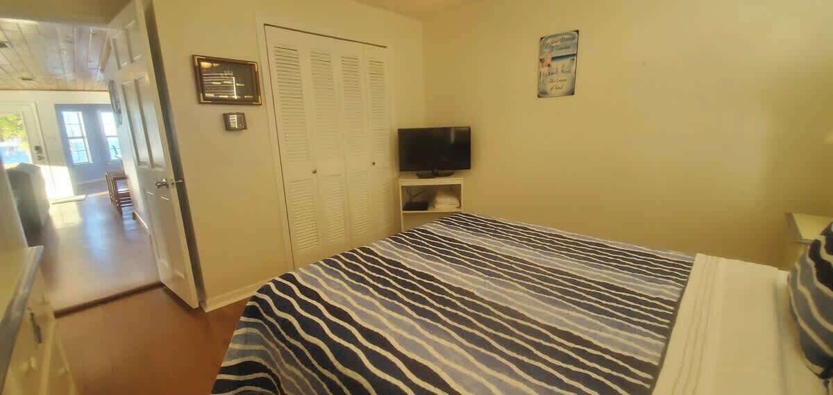 A bedroom with a zebra-striped bedspread, a television on a shelf, and a door leading to another room.