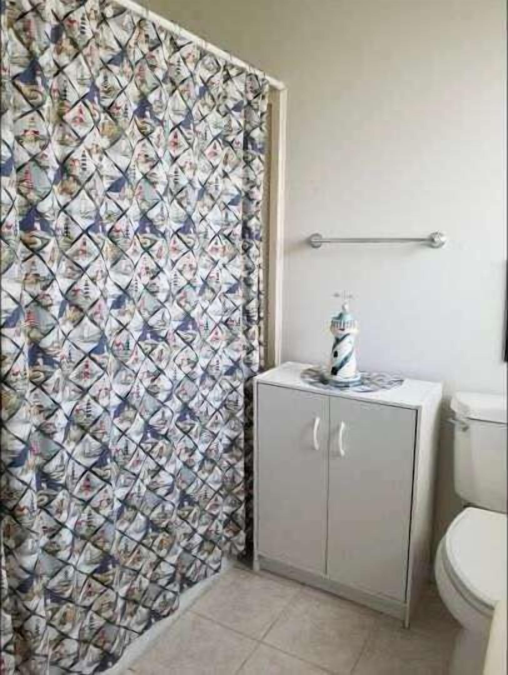 A bathroom with a patterned shower curtain, a cabinet, and a toilet.