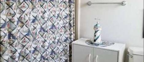 A bathroom with a patterned shower curtain, a cabinet, and a toilet.
