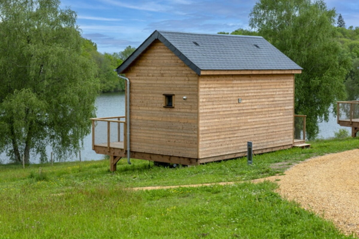 En stuga av trä med ett sluttande tak, ett litet fönster och en veranda.