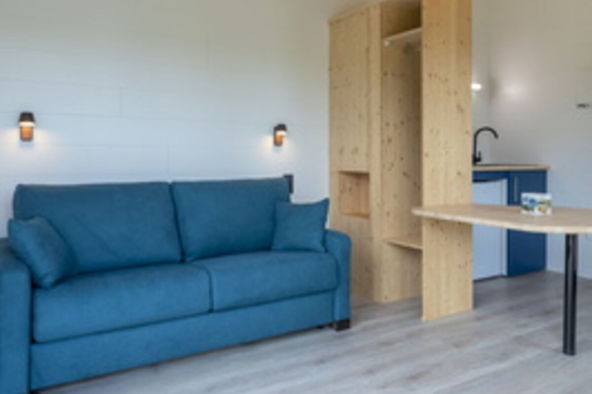 A room with a blue sofa, a wooden cabinet, and a small table.