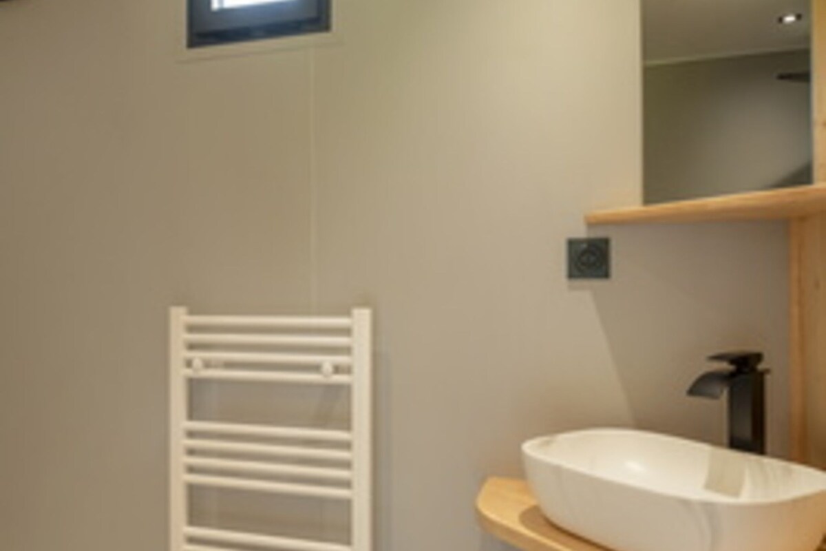 A modern bathroom with a white bathtub, a towel rack, and a mirror.
