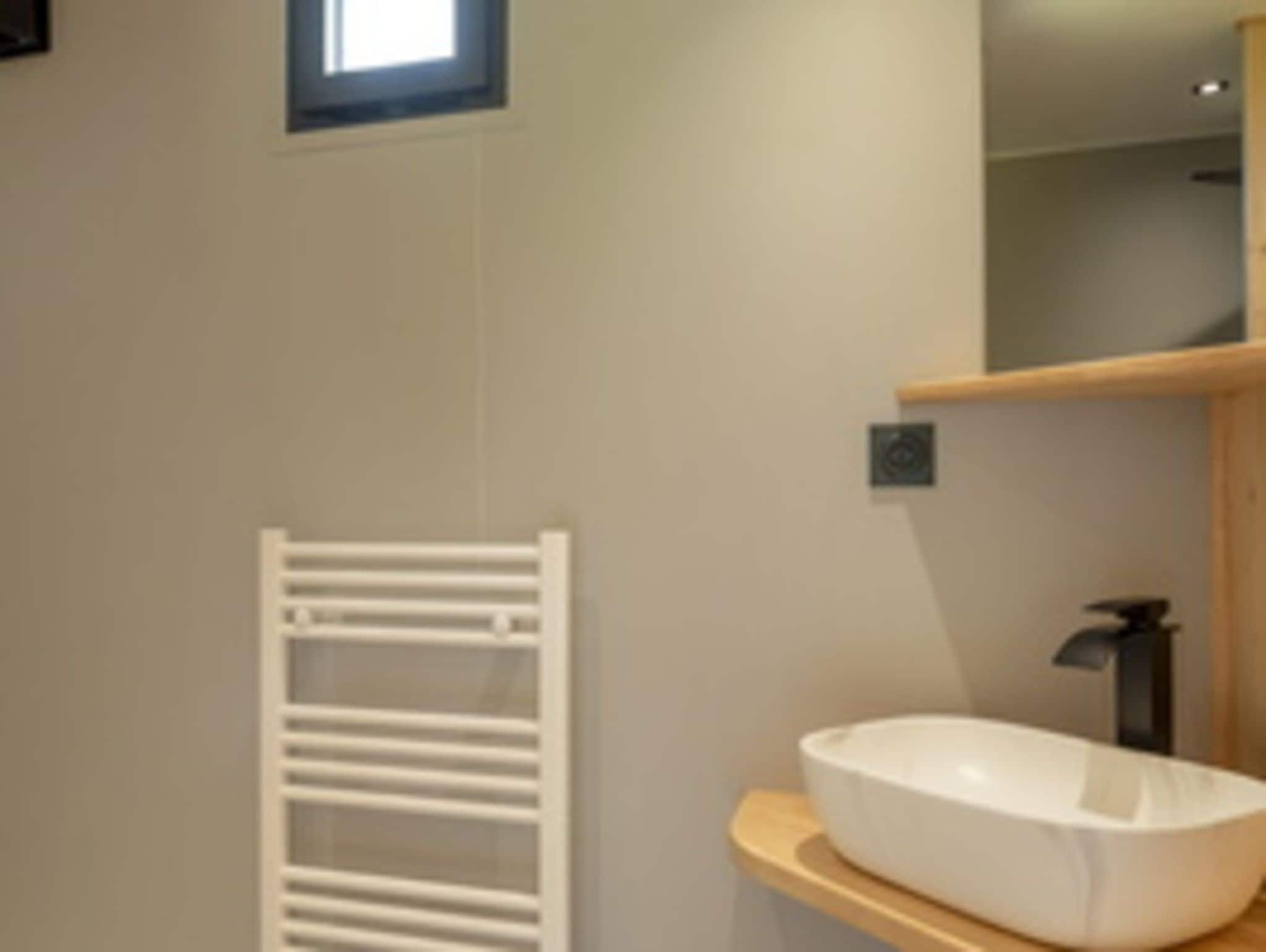 A modern bathroom with a white bathtub, a towel rack, and a mirror.
