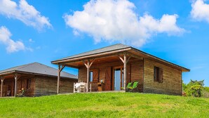 Una baita in legno con veranda, un'area salotto esterna coperta e un prato.