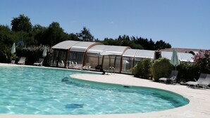 Un espace piscine avec des chaises longues et un coin salon abrité.