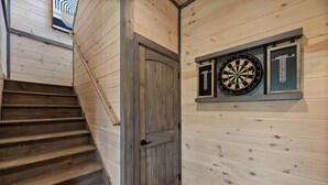 A wooden staircase leading to a door, with dartboards mounted on the wall above. - BRADN NEW Luxury Cabin! The ELM/PanoramicMountainView/Modern/LARGE DECKs (Gatlinburg)