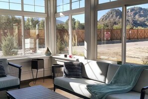 A sunroom with a large window, a sofa, a small table, and a chair.