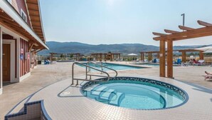 Ein Poolbereich mit Whirlpool, Liegestühlen und Blick auf die Berge.
