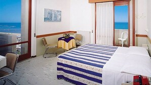 A hotel room with a bed, a chair, a small table with a tablecloth, a telephone, and a view of the sea. - Hotel International (Senigallia)