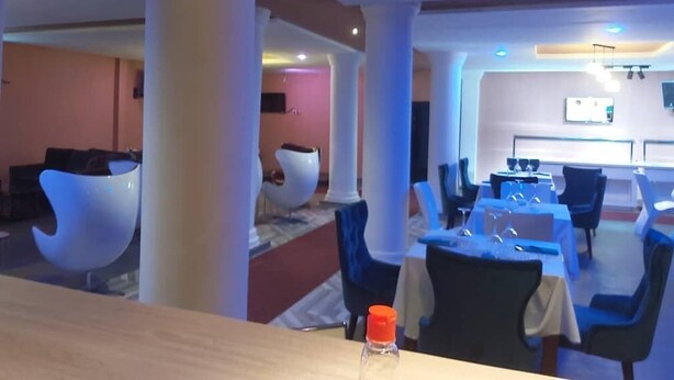 Een eethoek met tafels, stoelen en een fles op een tafel.
