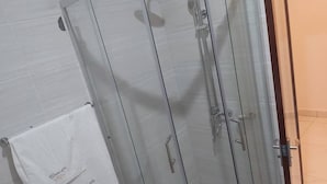 Een douchecabine met glazen wanden en een handdoek aan de muur.