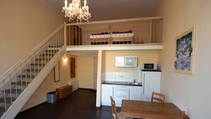 Un apartamento de dos pisos con una escalera, un comedor, una cocina y un dormitorio tipo loft.