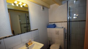 Un baño con lavamanos, espejo, inodoro y cabina de ducha de vidrio.