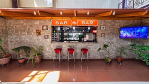 A bar area with a stone wall, a wooden ceiling, and a television screen. - OshNuru (Osh)