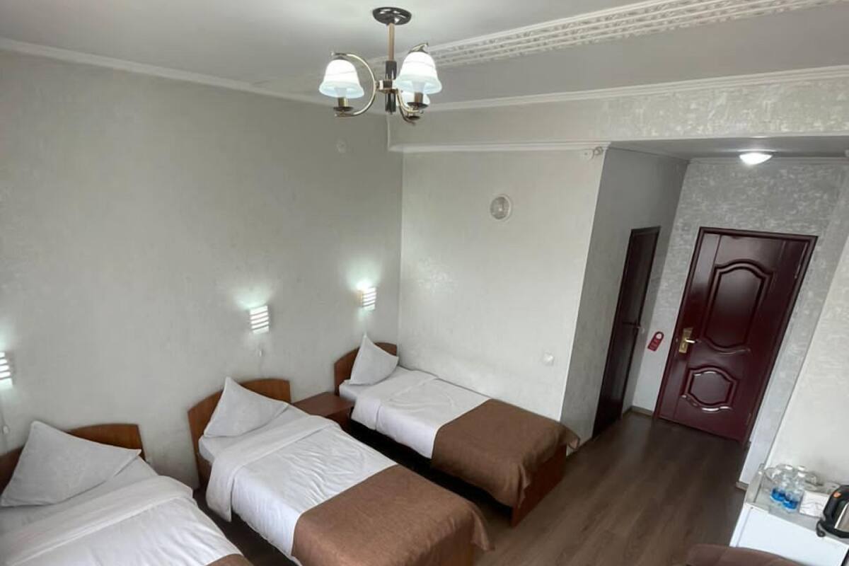 Ein Hotelzimmer mit zwei Betten, Holzboden, einer kleinen Sitzecke und einer Tür zu einem weiteren Raum.