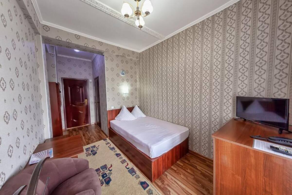 Ein Hotelzimmer mit Bett, Schreibtisch mit Fernseher und einer Wand mit Muster.