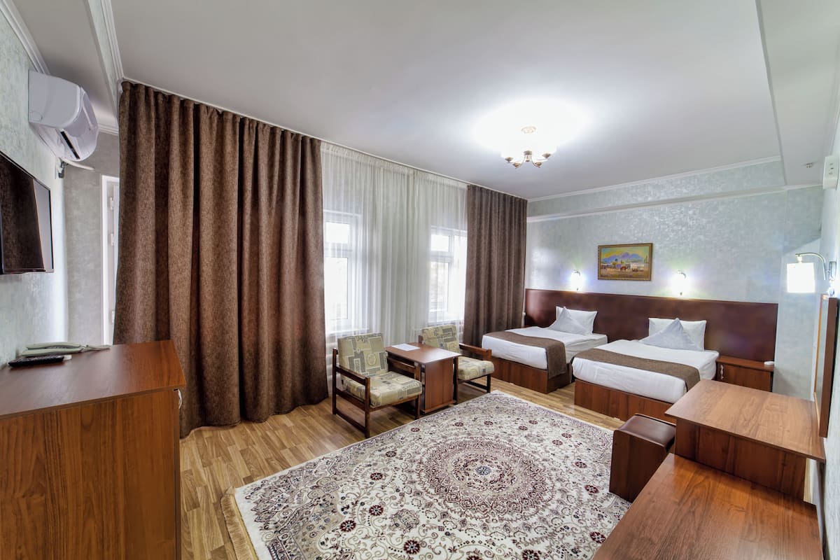 Ein Hotelzimmer mit zwei Betten, einem Schreibtisch, einem Stuhl, einem Teppich und einem Bild an der Wand.