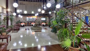 A spacious lobby with leather seating, a central fountain, and multiple hanging lights. - OshNuru (Osh)