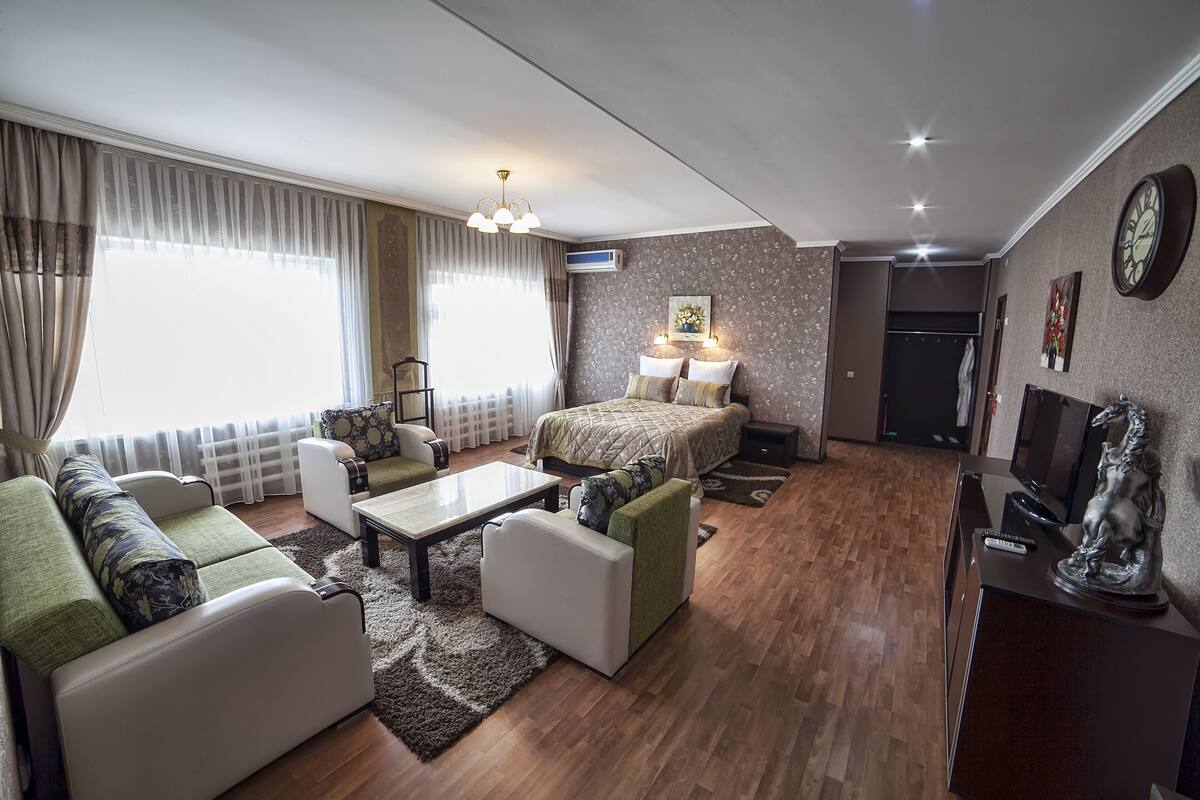 Ein modernes Wohnzimmer mit einer Couch, einem Couchtisch, einem Fernseher und einem Bett.