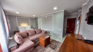 A modern living room with a pink sofa, a wooden coffee table, and a TV mounted on the wall. - OshNuru (Osh)