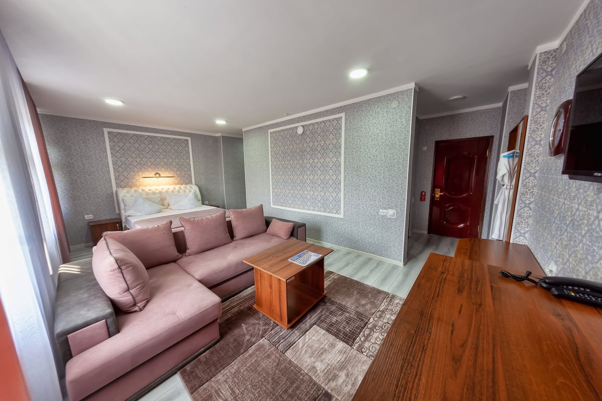 Ein modernes Wohnzimmer mit einem rosafarbenen Sofa, einem Holztisch und einem an der Wand befestigten Fernseher.