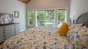 Ein Schlafzimmer mit einem großen Bett, einem Schminktisch, einem Fernseher und einem Balkon mit Tisch und Stühlen.