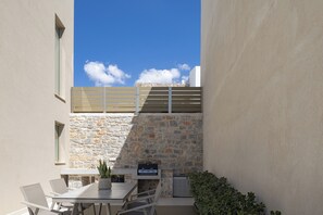 Un patio con un muro in pietra, un barbecue e un tavolo con sedie.