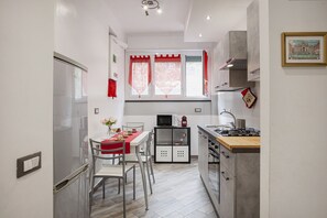 A compact kitchen with a dining area, a microwave, a gas stove, and a small cabinet.