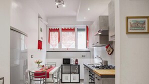 A compact kitchen with a dining area, a microwave, a gas stove, and a small cabinet. - La casa di Lorenzo by Wonderful Italy (Genova)