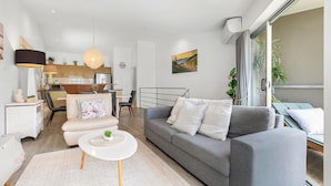 Un soggiorno moderno con un divano grigio, un tavolino da caffè bianco rotondo e un'area pranzo con mobili in legno.
