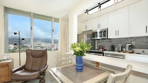 A modern kitchen with white cabinets, stainless steel appliances, and a view of the city. - HIGH Floor w/Canal, Mtn and Partial Ocean Views! AC, W/D, WiFi, Pool,Parking! (Honolulu)