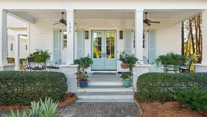 A covered porch with a double door, potted plants, and a bench.
