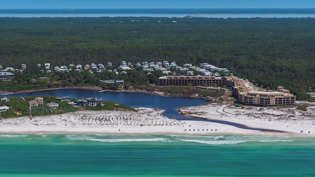 A coastal resort with beachfront villas, a central water body, and dense forested areas.