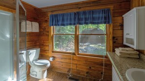 Baño de cabaña de madera con inodoro, lavabo y ventana.