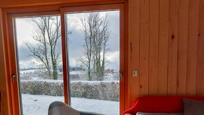 A cozy room with a red sofa, a checkered chair, and a wooden floor. - Domaine Taureau, Morvan Regional Nature Park (Saint-Brisson)