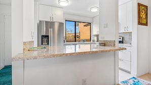 A modern kitchen with white cabinetry, stainless steel appliances, and a large island. - Wailea Ekahi 36E | Tropical Retreat with Beach Access and 4 Pools (Wailea)