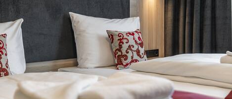 A hotel room with a bed, two pillows, a blanket, and a wall-mounted light.
