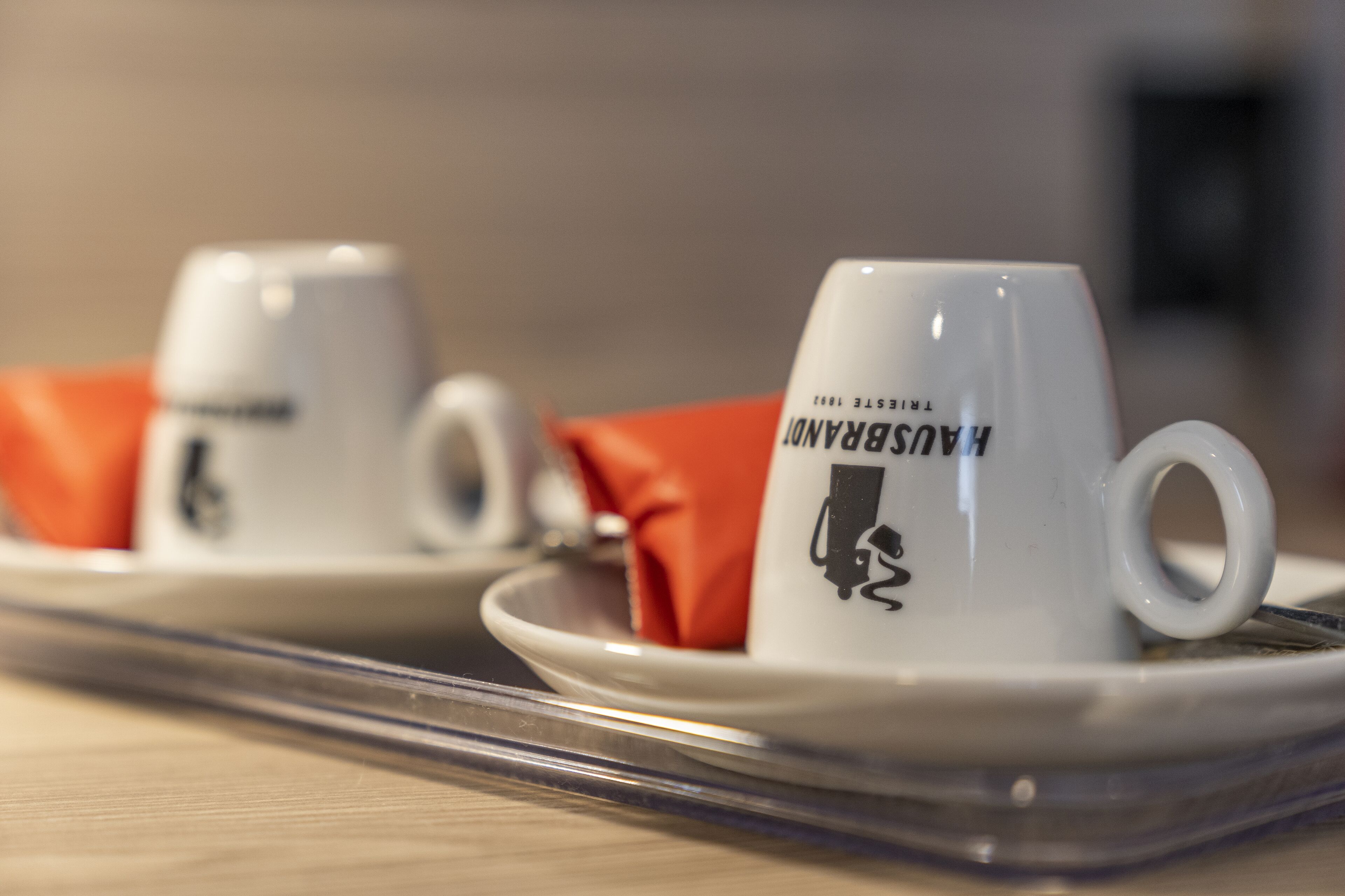 Two white cups with a logo on a tray.