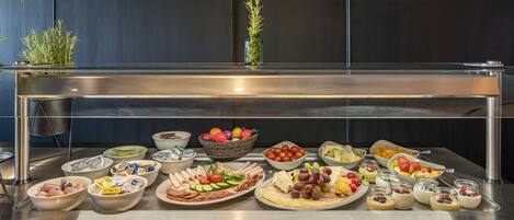 A buffet with various food items including fruits, cheeses, and meats.