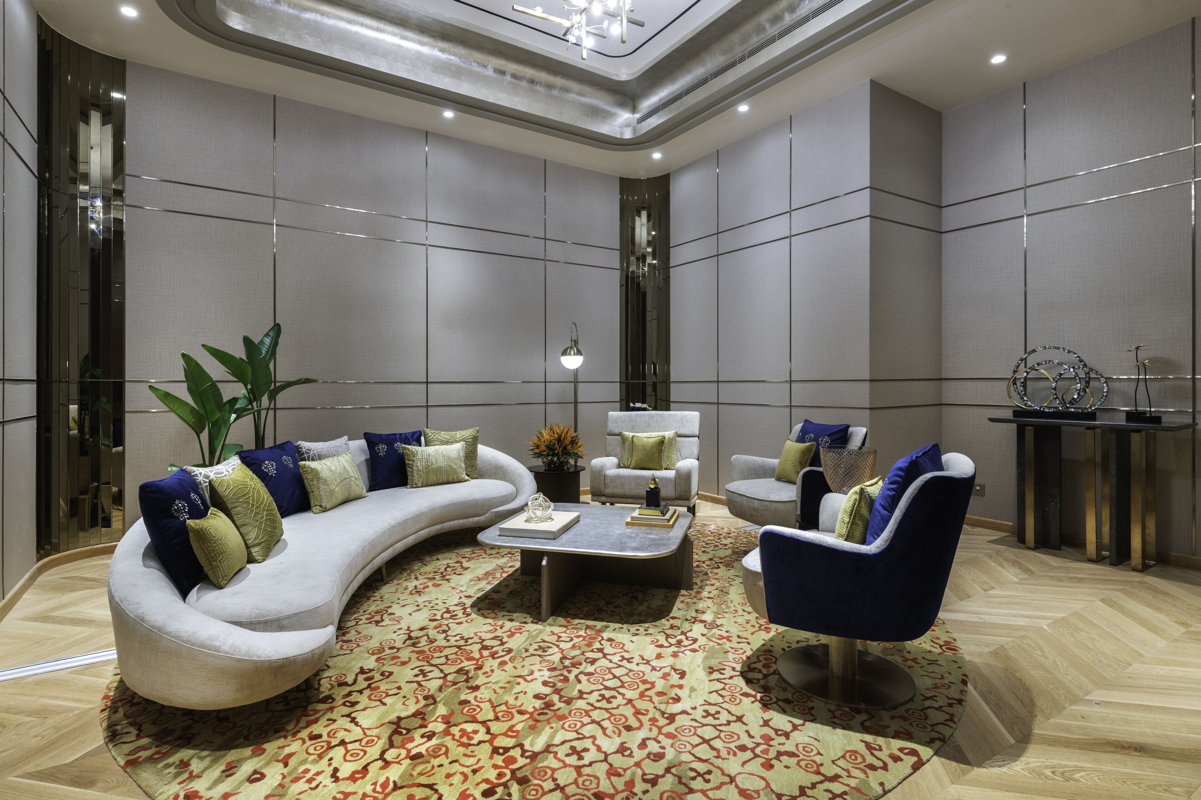 A modern living room with a curved sofa, a blue armchair, and a coffee table.