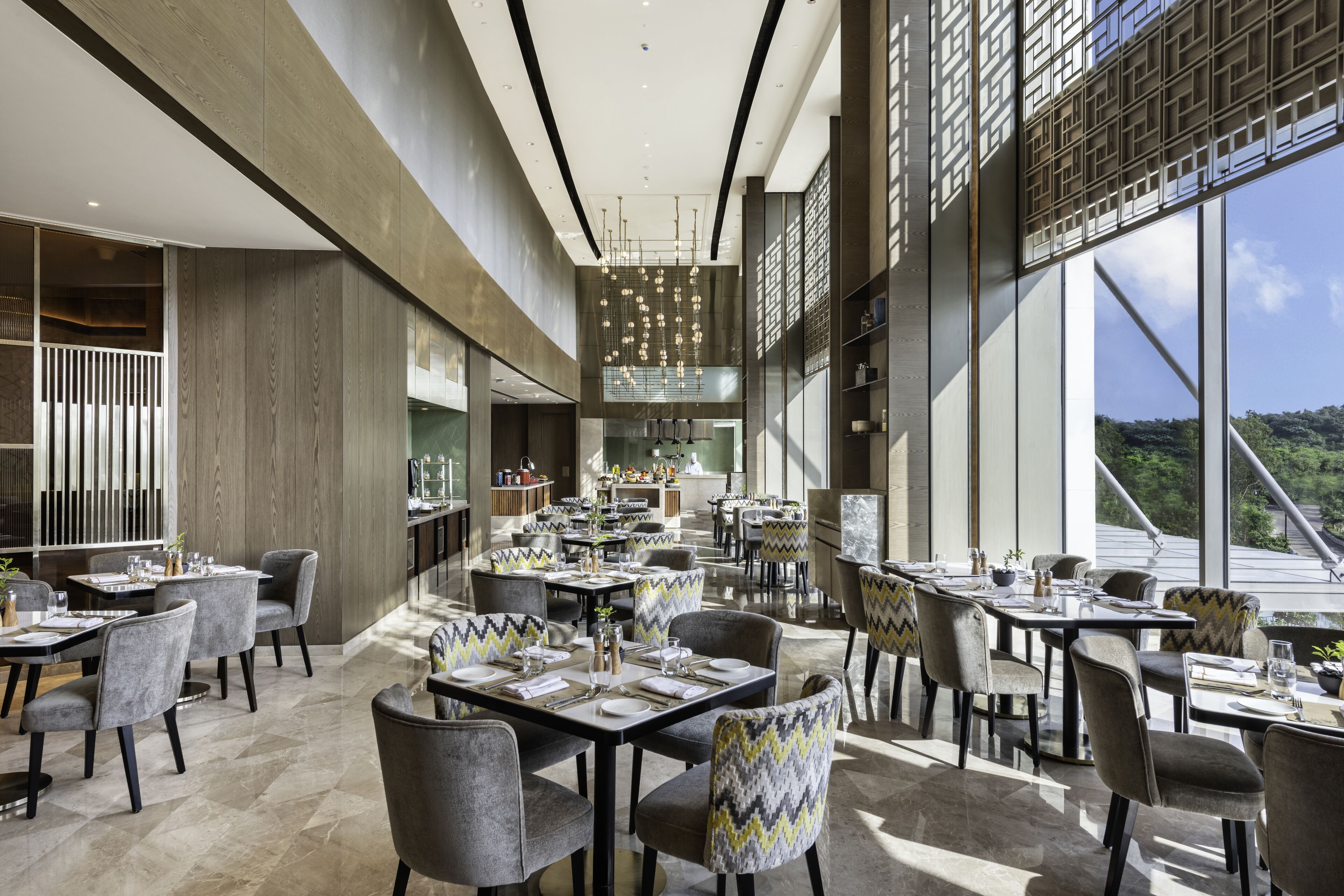 Un amplio comedor con varias mesas y sillas, ventanas grandes que ofrecen vistas al exterior, y un diseño de interiores moderno.