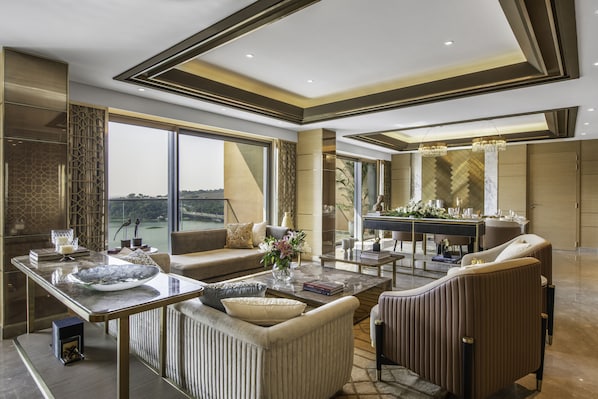 A spacious living area with a large window, a dining table, and comfortable seating. - Taj Lakefront Bhopal (Bhopal)